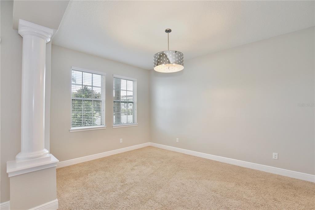An empty room with beige carpet, light walls, two windows, and a decorative column — 5332 FACTORS WALK DRIVE, SANFORD, FL