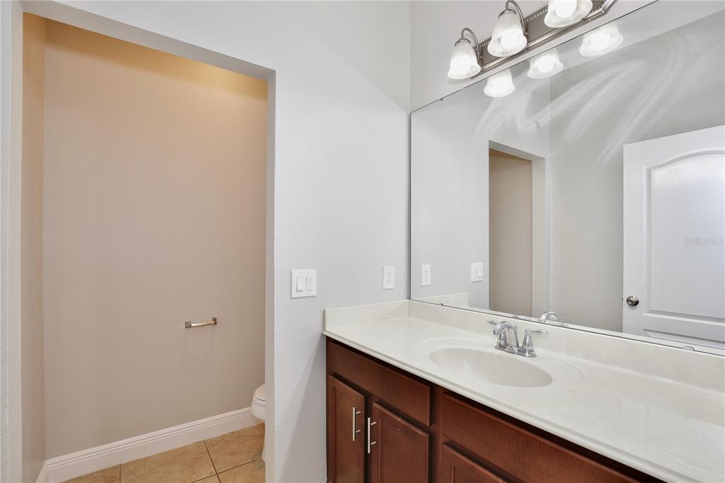 A bathroom features a dark wood vanity with a white countertop and a large wall mirror — 5332 FACTORS WALK DRIVE, SANFORD, FL