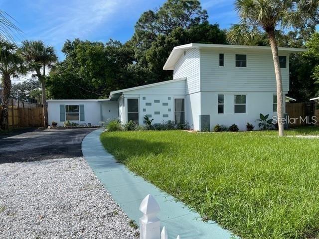 A two-story light blue house features a white gravel driveway and a green walkway — 415 VENETIAN DRIVE, CLEARWATER, FL