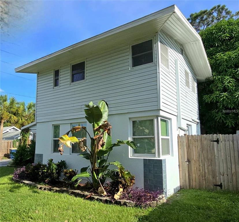 A two-story house features white horizontal siding on the upper level and white stucco below — 415 VENETIAN DRIVE, CLEARWATER, FL