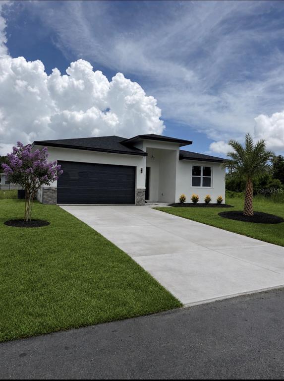 A modern single-story house with a white exterior, dark garage door, and a concrete driveway — 1681 WELLAND STREET SE, PALM BAY, FL
