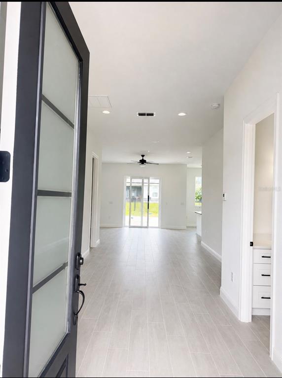 An entryway opens into a long, open-concept living area with light tile flooring and recessed lighting — 1681 WELLAND STREET SE, PALM BAY, FL