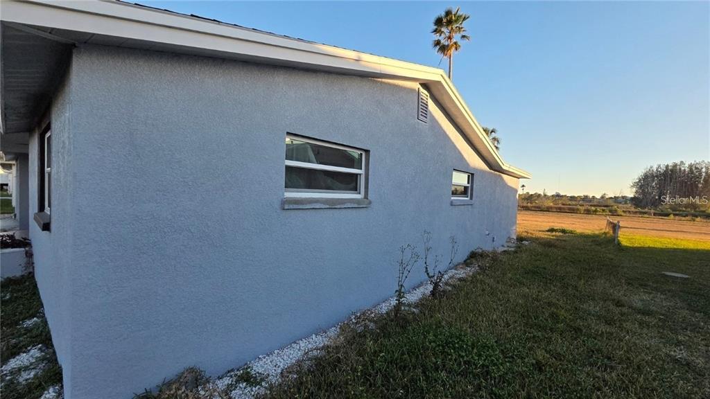 The exterior side wall of a blue stucco house features two windows and white trim — 4020 HEADSAIL DRIVE, NEW PORT RICHEY, FL