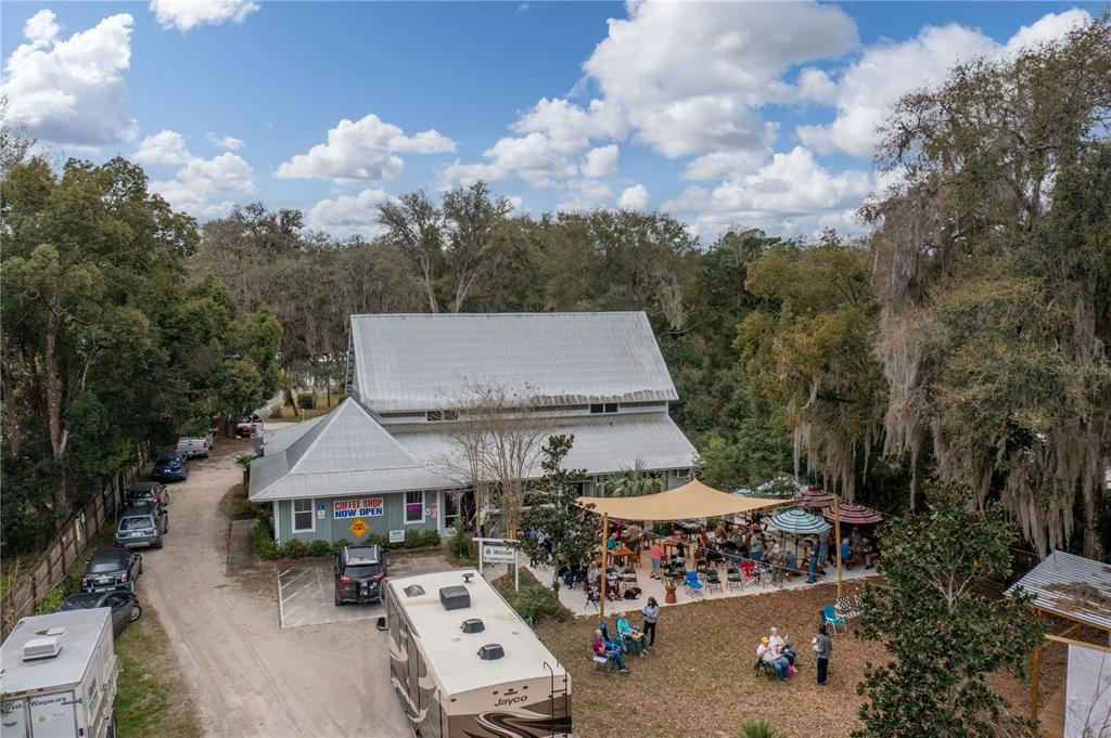 An aerial view shows a building with a coffee shop, outdoor seating, and parked vehicles — 307/309 STATE ROAD 26, MELROSE, FL