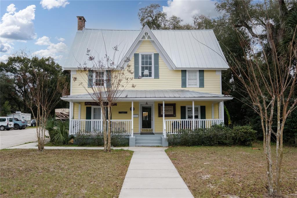 A two-story yellow house with a metal roof and a front porch sits on grass — 307/309 STATE ROAD 26, MELROSE, FL