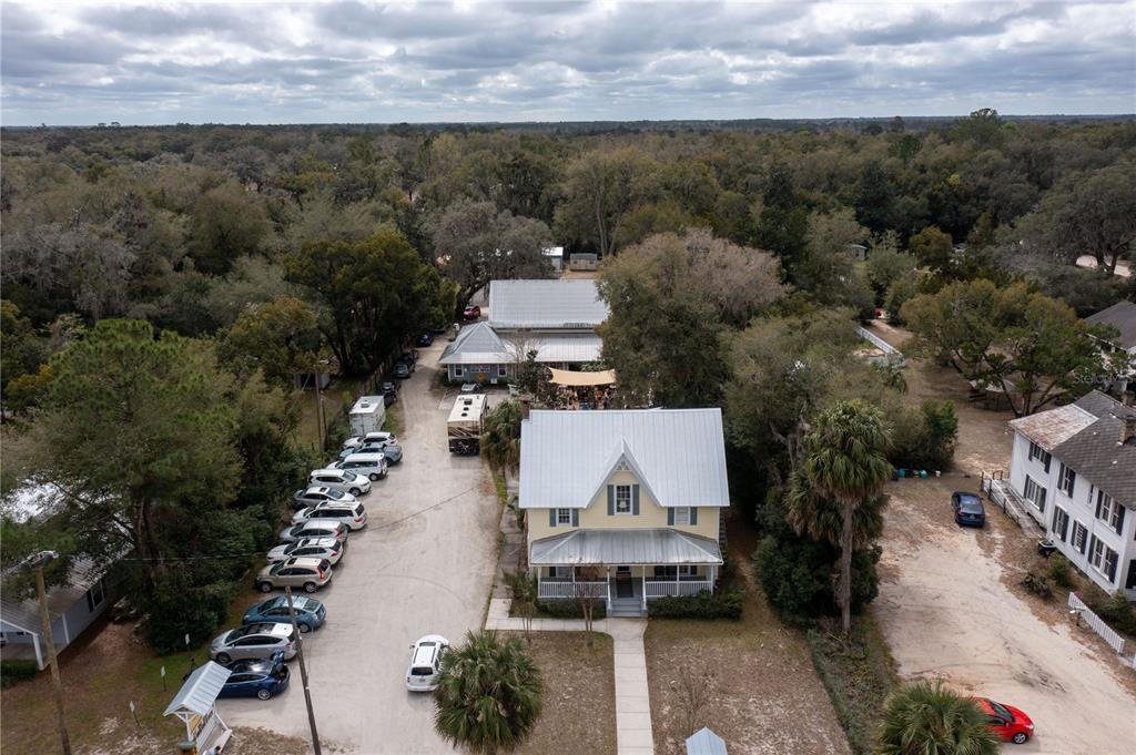 An aerial view shows a yellow house with a metal roof and a parking lot — 307/309 STATE ROAD 26, MELROSE, FL