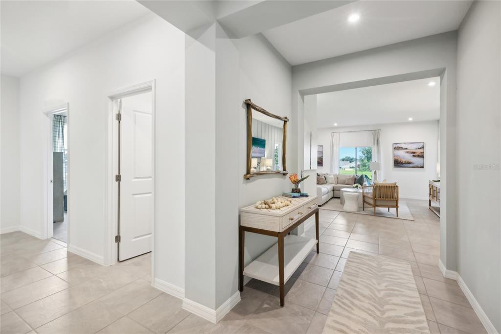 A hallway with tile floors leads to an open living area with a console table — 12918 CARA COURT, GRAND ISLAND, FL