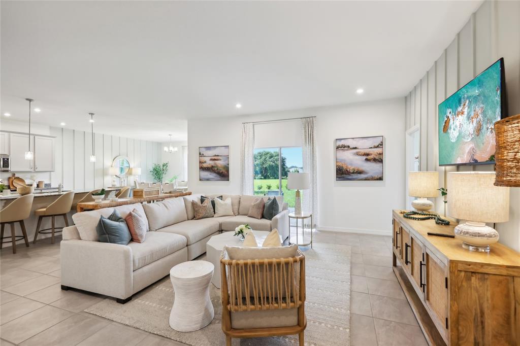 A bright living room features a sectional sofa, a wooden console, and a kitchen area — 12918 CARA COURT, GRAND ISLAND, FL