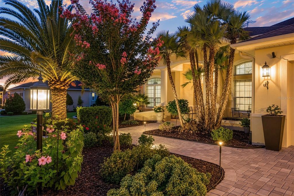 A paved walkway leads to the entrance of a house surrounded by palm trees and landscaping — 622 LAUREL RUN, THE VILLAGES, FL