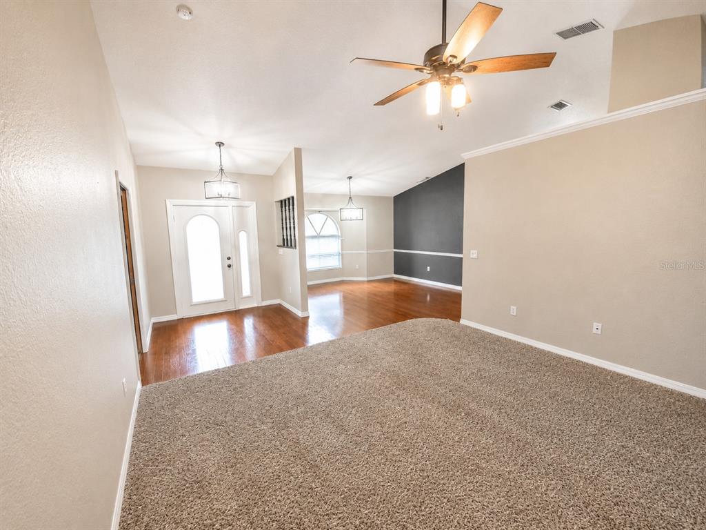 A living room with beige carpet, hardwood flooring in the entryway, and a ceiling fan — 3095 SCHOMER STREET, NORTH PORT, FL