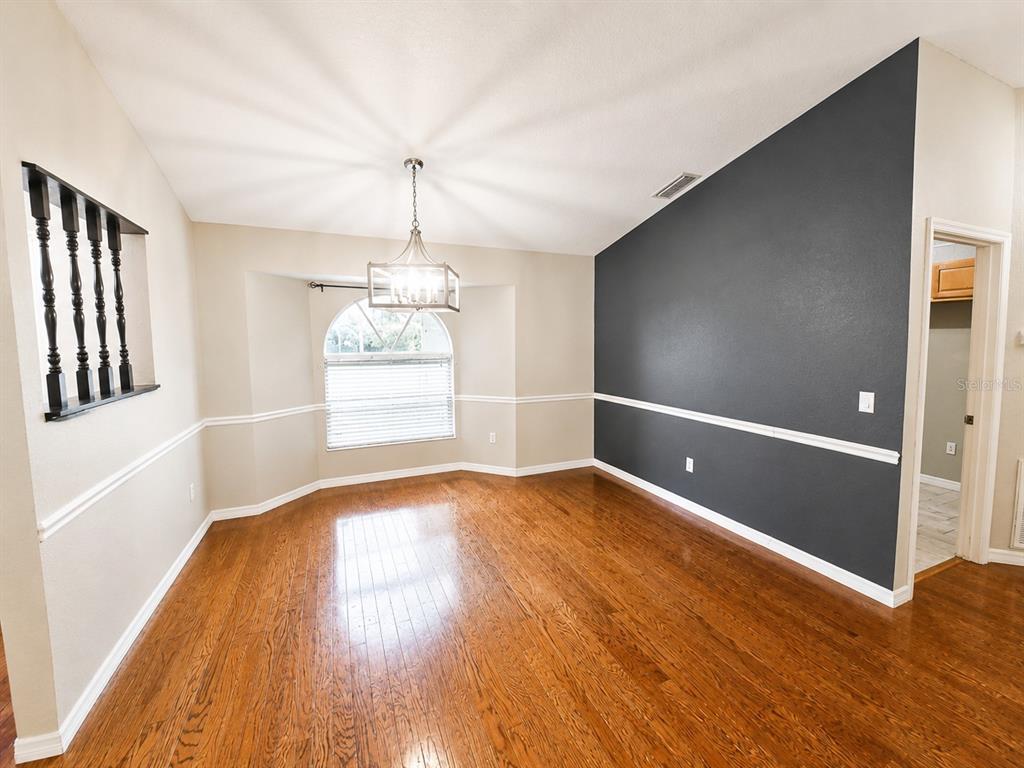 A dining room features hardwood floors, a vaulted ceiling, a chandelier, and a dark accent wall — 3095 SCHOMER STREET, NORTH PORT, FL