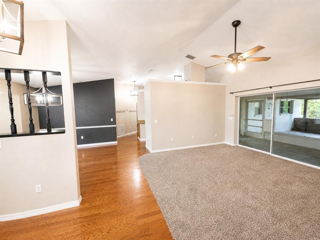 A living room features hardwood flooring, carpet, a ceiling fan, and sliding glass doors — 3095 SCHOMER STREET, NORTH PORT, FL