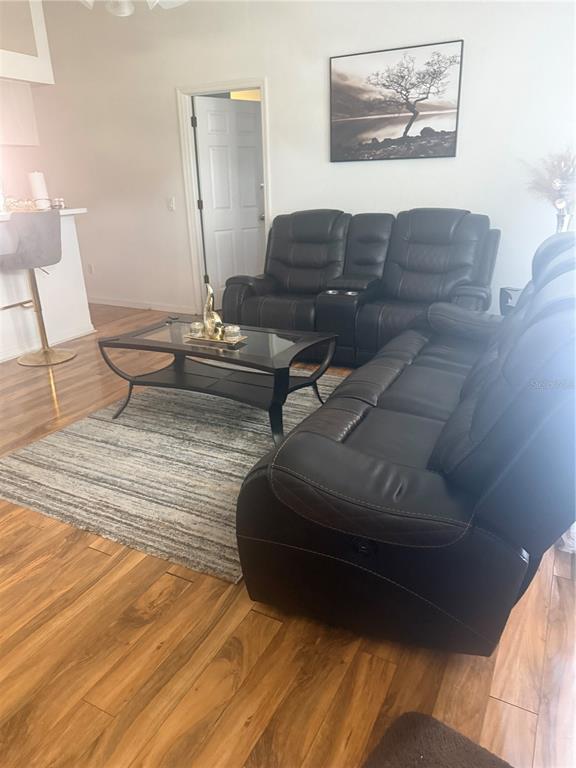 A living room features dark leather reclining sofas, a glass coffee table, and wood flooring — 7455 W PRICE BOULEVARD, NORTH PORT, FL