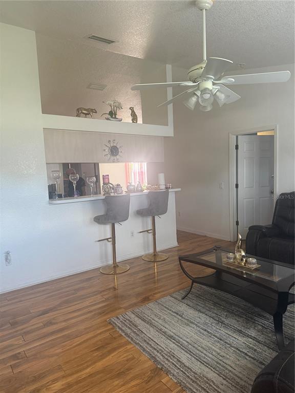 A living room features wood-look flooring, a breakfast bar with two stools, and a ceiling fan — 7455 W PRICE BOULEVARD, NORTH PORT, FL