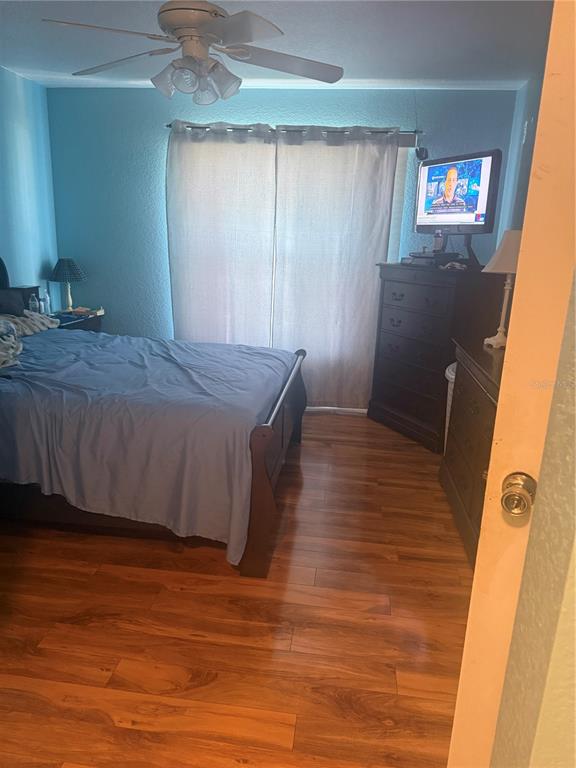 A bedroom with light blue walls, wood-look flooring, a ceiling fan, and a dark wood dresser — 7455 W PRICE BOULEVARD, NORTH PORT, FL