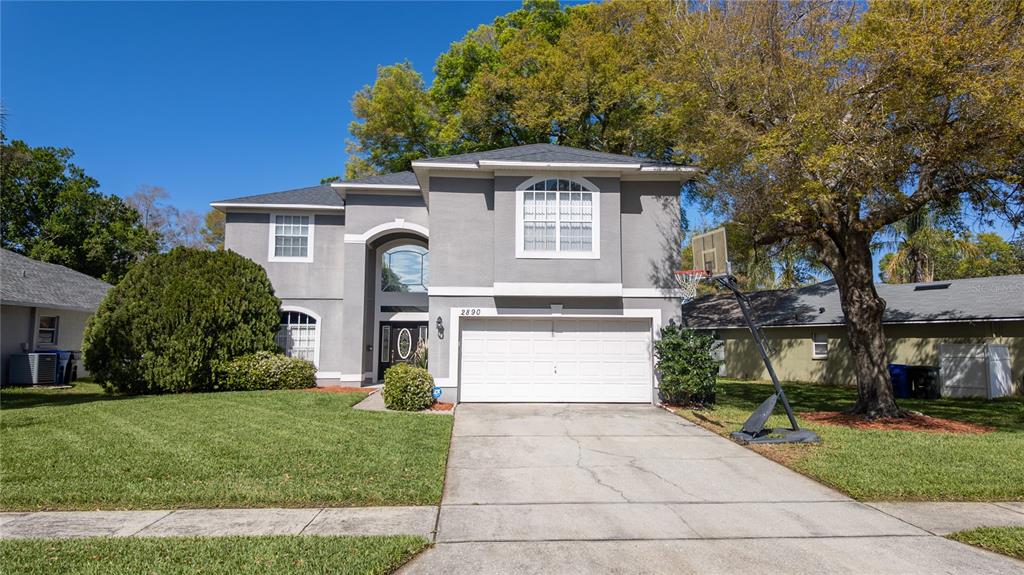 A two-story gray house with a white garage door and a basketball hoop in front — 2890 CULLENS COURT, OCOEE, FL