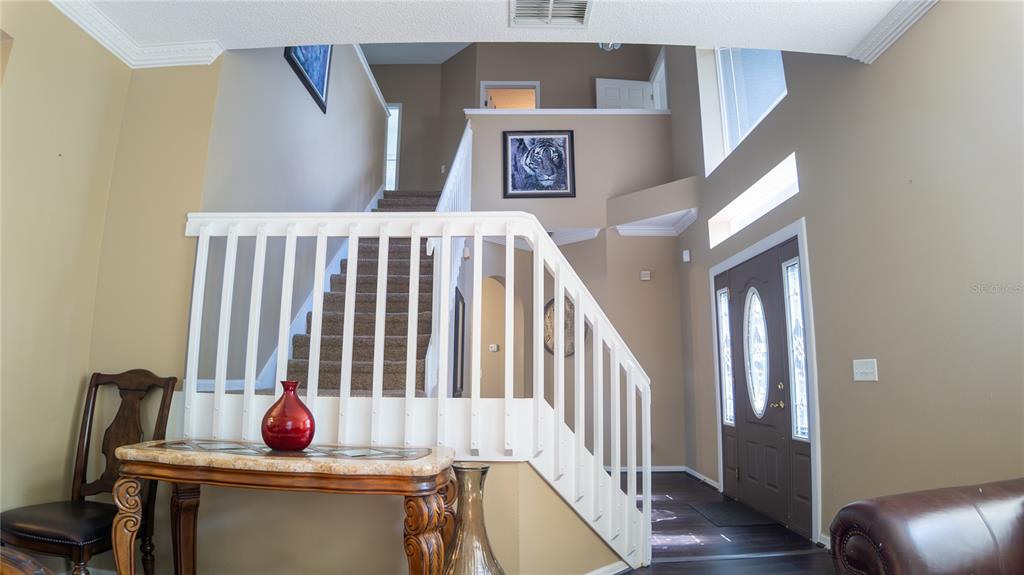 A foyer features a staircase with white railings, a console table, and a front door — 2890 CULLENS COURT, OCOEE, FL