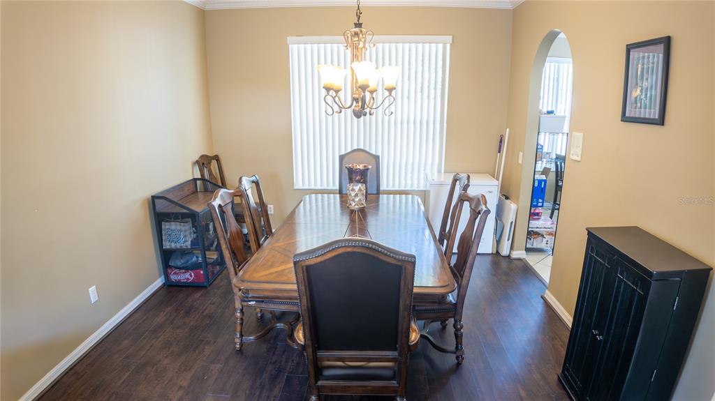 A dining room features a wooden table, six chairs, a chandelier, and dark wood flooring — 2890 CULLENS COURT, OCOEE, FL