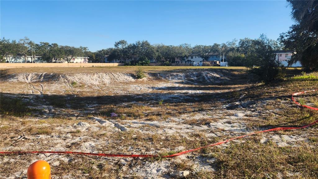 A large, vacant, sandy lot is enclosed by red caution tape under a clear sky — DRUID ROAD E, CLEARWATER, FL