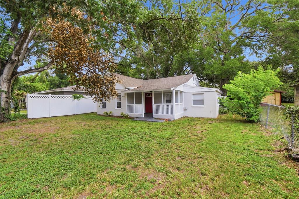 A single-story house with a white porch, red front door, and a large grassy yard — 4209 N DOWNING AVENUE, TAMPA, FL