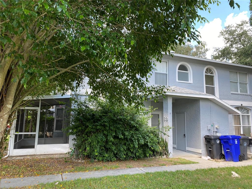 A two-story light blue townhouse with a screened-in porch and a front entrance — 62 EMERALD BAY DRIVE, OLDSMAR, FL