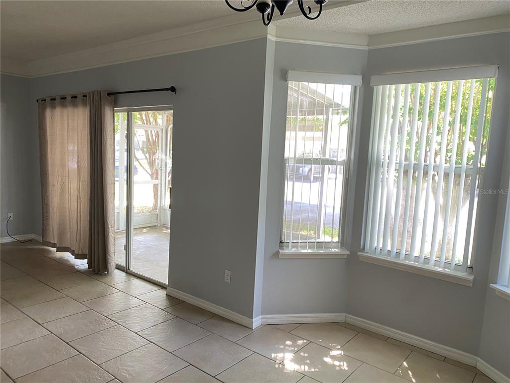 A room with light blue walls, tile flooring, a sliding glass door, and bay windows — 62 EMERALD BAY DRIVE, OLDSMAR, FL