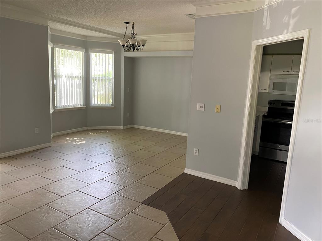 An interior view shows a dining area with tile floors and a nearby kitchen entrance — 62 EMERALD BAY DRIVE, OLDSMAR, FL