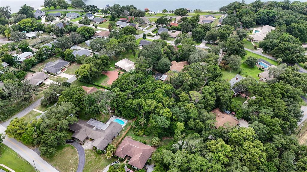 An aerial view shows a residential neighborhood with houses, swimming pools, and dense tree cover — FAIRWAY AVENUE, EUSTIS, FL