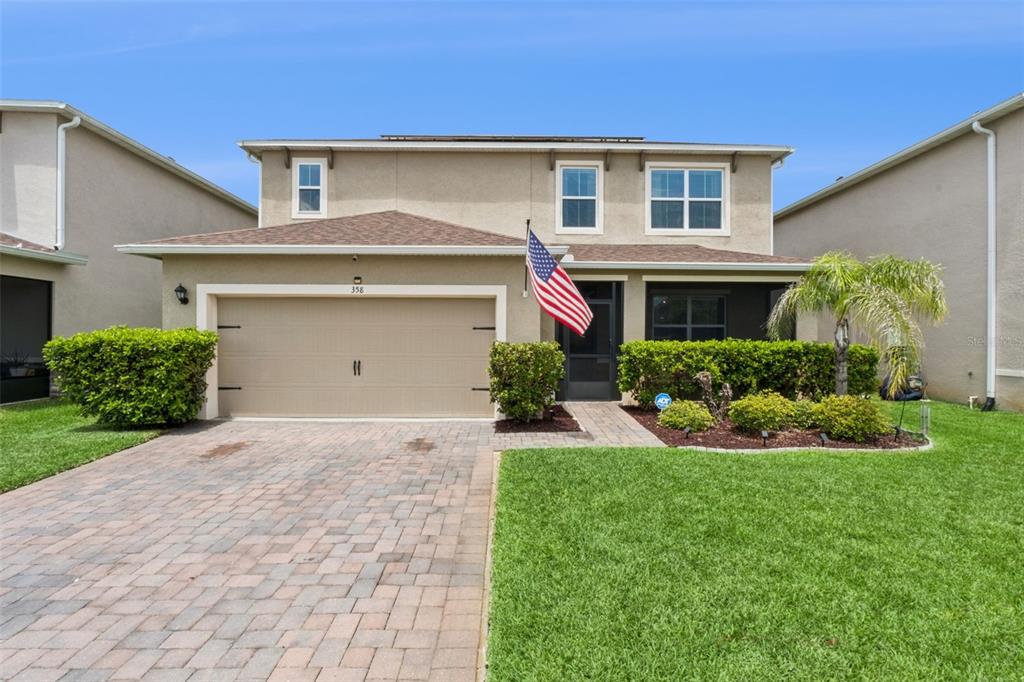 A two-story house with a tan stucco exterior, a two-car garage, and a paved driveway — 358 LAZIO CIRCLE, DEBARY, FL