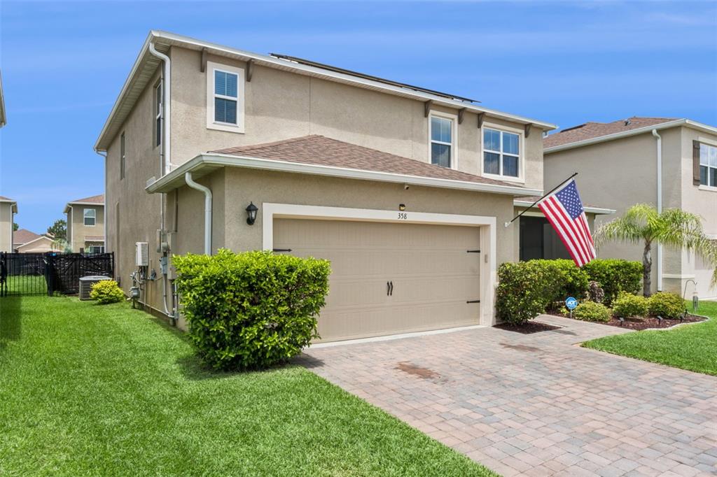A two-story house with a beige stucco exterior, a paved driveway, and an attached garage — 358 LAZIO CIRCLE, DEBARY, FL