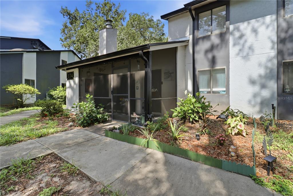A two-story residential building with a screened-in front porch and a landscaped garden bed — 174 WATERFALL WAY UNIT 101, ALTAMONTE SPRINGS, FL
