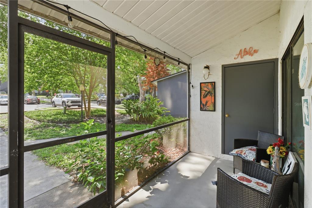 A screened-in porch features a gray door, wicker chairs, and a view of the street — 174 WATERFALL WAY UNIT 101, ALTAMONTE SPRINGS, FL