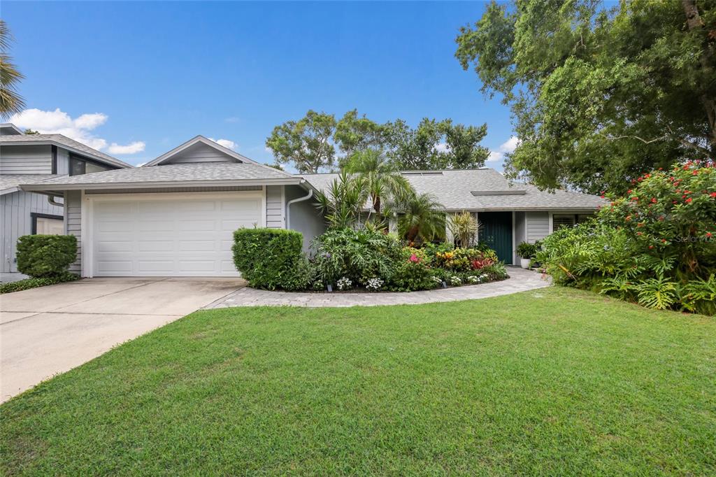 A gray single-story house with a white garage door and lush landscaping in the front — 851 FAULKWOOD COURT, SARASOTA, FL