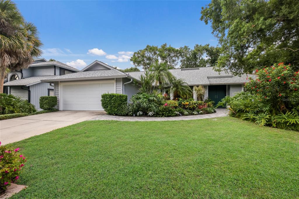 A paved walkway leads to the front entrance of a house surrounded by lush landscaping — 851 FAULKWOOD COURT, SARASOTA, FL