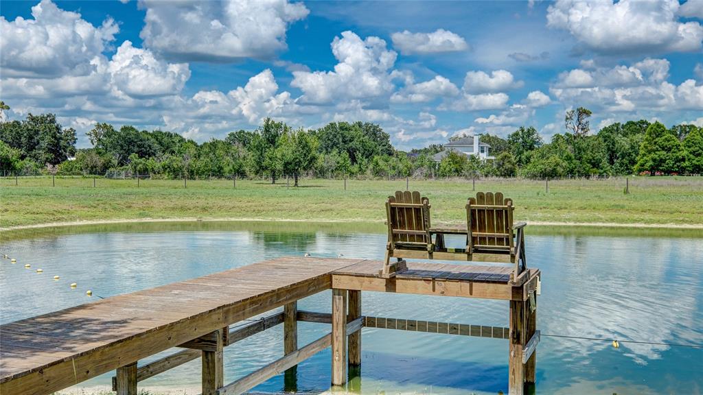 A tan house with a screened-in porch stands in a large, grassy yard with trees — 560 OAKFORD ROAD, SARASOTA, FL