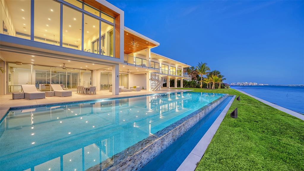 A modern two-story waterfront home features a large infinity pool, glass walls, and a lawn — 4123 BAY SHORE ROAD, SARASOTA, FL