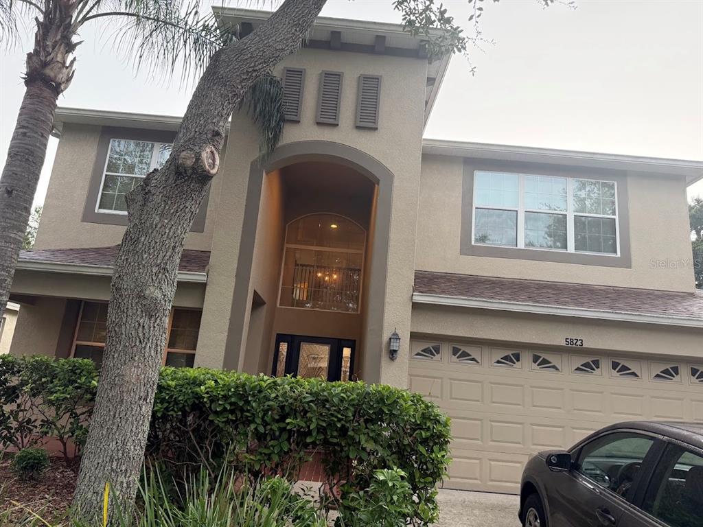 A two-story house with a beige stucco exterior, a multi-car garage, and a palm tree — 5823 BUTTERFIELD STREET, RIVERVIEW, FL