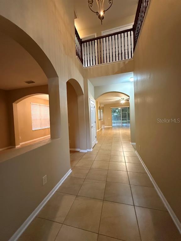 A tiled entryway leads to a two-story foyer with a balcony and arched wall openings — 5823 BUTTERFIELD STREET, RIVERVIEW, FL