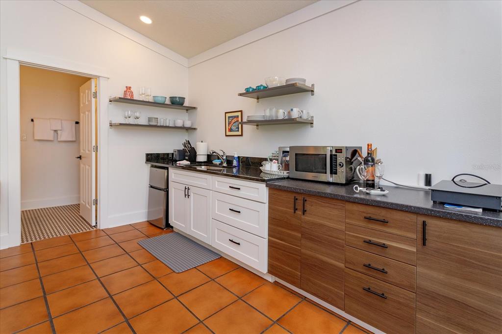 A kitchen area features white and wood-grain cabinets, dark countertops, open shelving, and tile flooring — 1802 CHAMBERLIN STREET, ORLANDO, FL