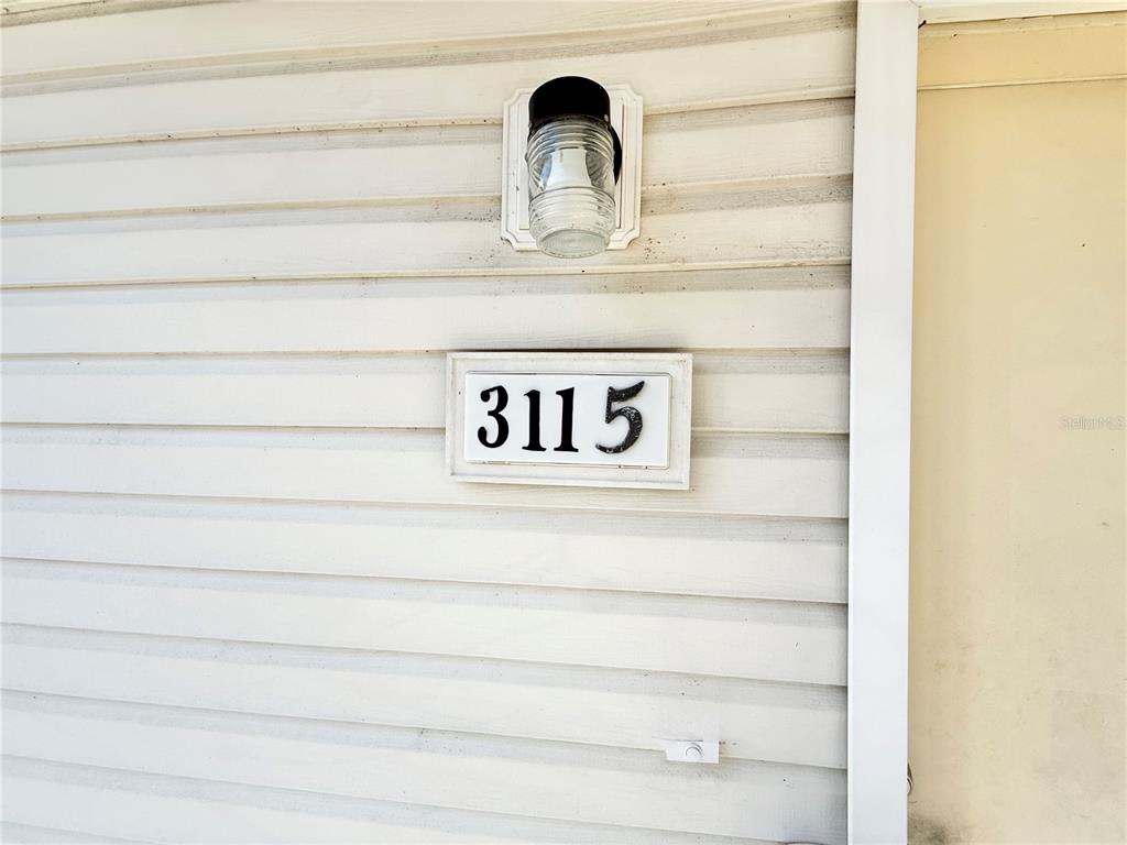 A house number plaque reading 3115 is mounted on white horizontal vinyl siding — 3115 FOX SQUIRREL DRIVE UNIT 3115, KISSIMMEE, FL