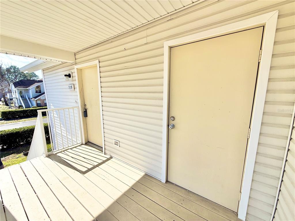 An exterior view of a wooden deck featuring two beige doors on a building — 3115 FOX SQUIRREL DRIVE UNIT 3115, KISSIMMEE, FL
