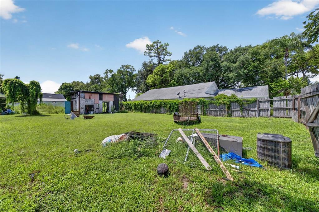 A grassy backyard features a small shed, a wooden fence, and scattered debris — NEUSE AVENUE, ORLANDO, FL
