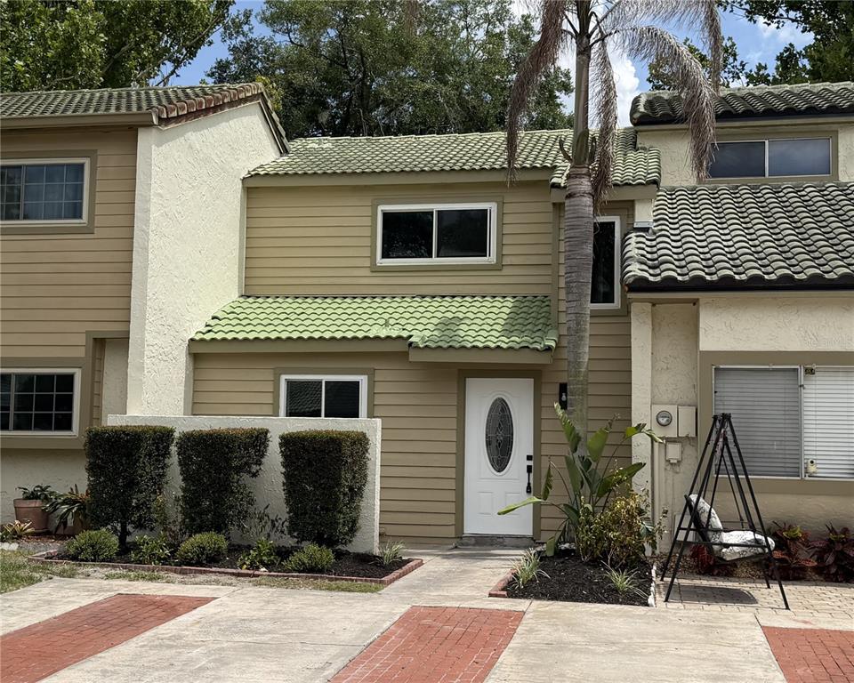 The exterior of a two-story townhouse features tan siding, green tile roofing, and a white door — 434 SAND LIME ROAD, WINTER GARDEN, FL