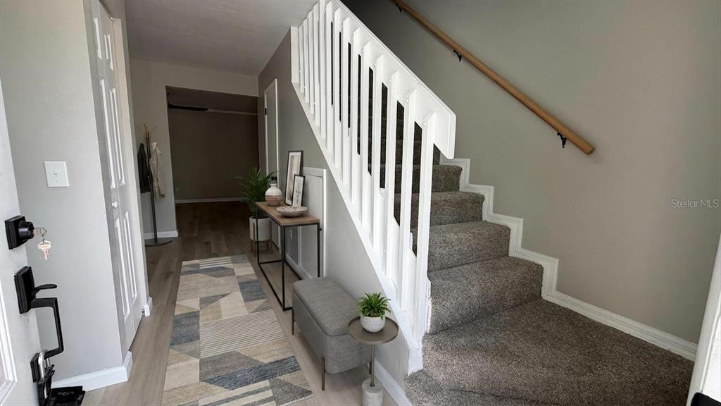 An entryway features a carpeted staircase with a white railing, a console table, and flooring — 434 SAND LIME ROAD, WINTER GARDEN, FL