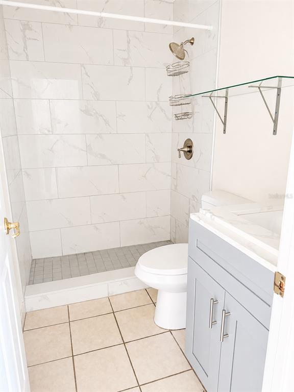 A bathroom features a tiled shower, a white toilet, and a gray vanity cabinet — 1290 9TH STREET UNIT 108, DAYTONA BEACH, FL
