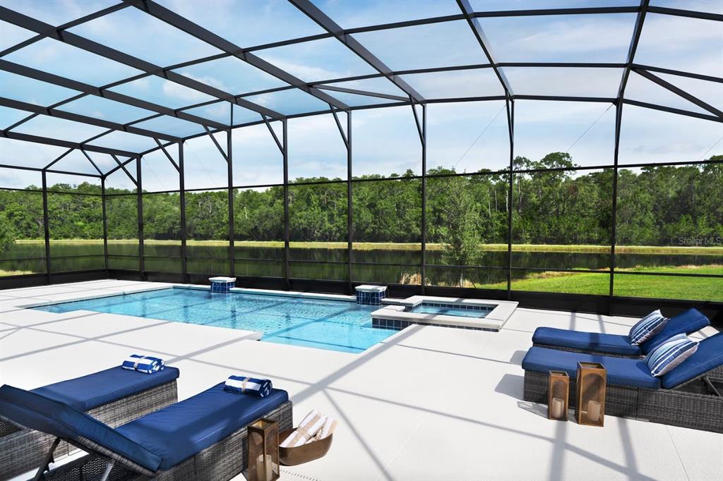 A screened-in pool and spa area with lounge chairs overlooking a lake and trees — 1422 BUTTERFLY MILKWEED COURT, DAVENPORT, FL