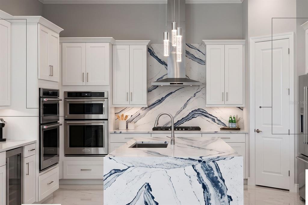 A modern kitchen features white cabinets, stainless steel appliances, and a bold blue-veined marble island — 1422 BUTTERFLY MILKWEED COURT, DAVENPORT, FL