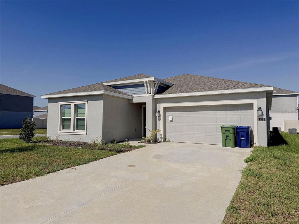 A single-story house with a light-colored stucco exterior, a two-car garage, and a concrete driveway — 652 REGGIE ROAD, WINTER HAVEN, FL