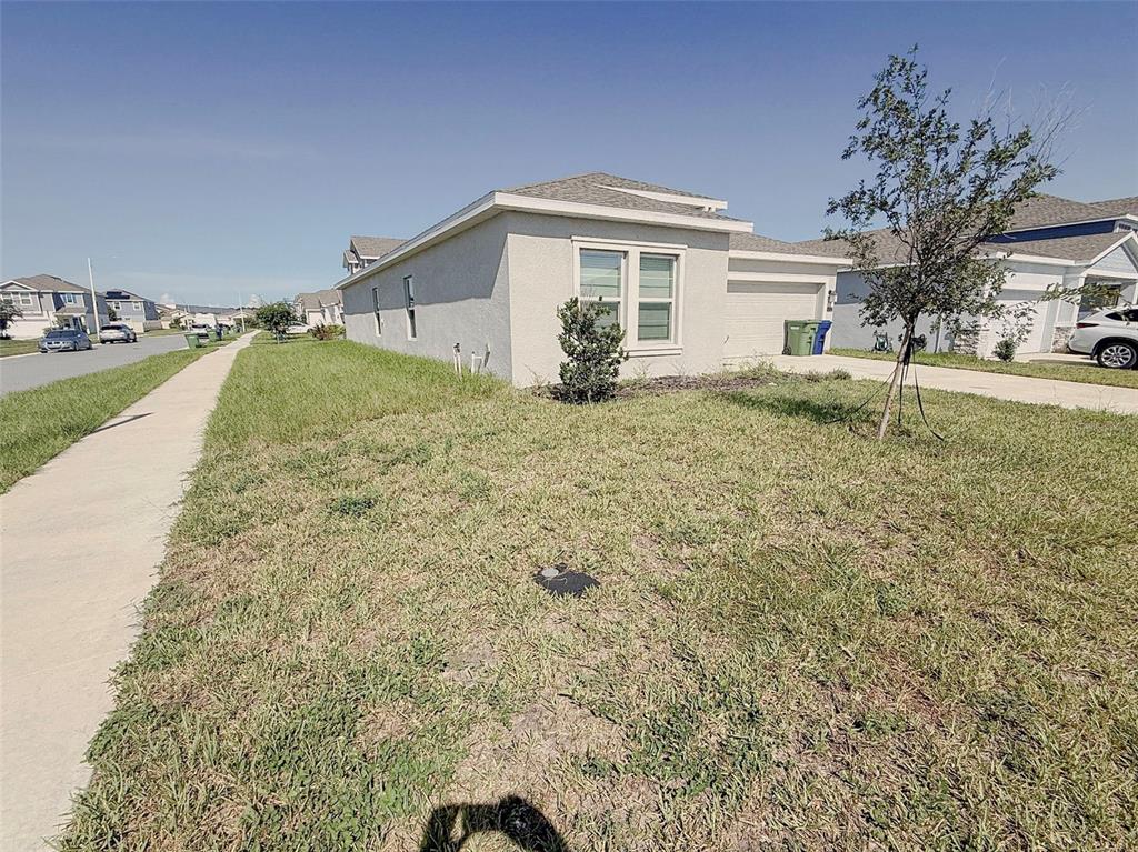 A single-story house with a light-colored stucco exterior and a concrete driveway — 652 REGGIE ROAD, WINTER HAVEN, FL