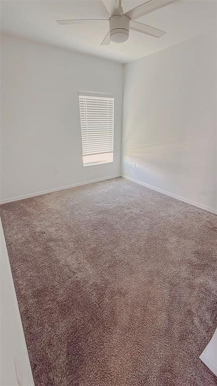 An empty bedroom features beige carpet, white walls, a ceiling fan, and a single window — 652 REGGIE ROAD, WINTER HAVEN, FL